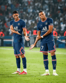 two soccer players wearing blue jerseys with all on them