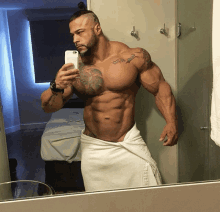 a muscular man taking a selfie in front of a mirror with a towel around his waist