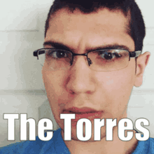 a man wearing glasses and a blue shirt with the words " the torres " on his face