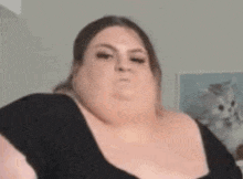 a very fat woman is making a funny face while looking at the camera .