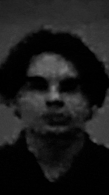 a black and white photo of a person 's face with a blurred background .