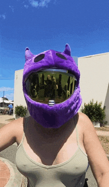 a woman wearing a purple helmet with devil horns