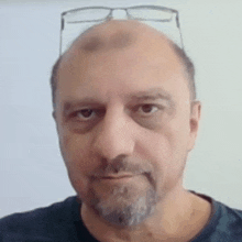 a bald man with a beard and glasses on his head .