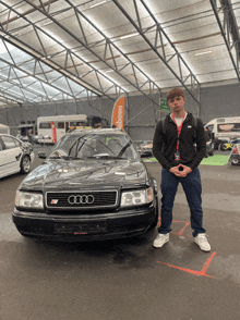 a man stands in front of a black audi