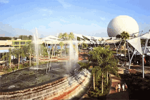 a fountain in a park with a large white ball in the background and the word cm on the bottom