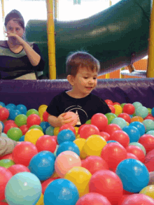 a young boy playing in a ball pit wearing a shirt that says ' i am a ninja ' on it