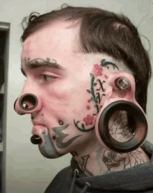 a man with a tattoo on his face and a lot of piercings on his face