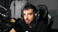 a man wearing headphones and a black shirt with a bottle of water behind him