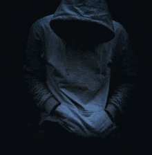 a person wearing a hoodie with their hands in their pockets in the dark