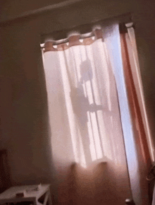 a shadow of a person is cast on a window through a pink curtain