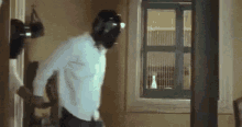 a man wearing a helmet is standing in a room with a window .