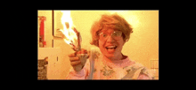 a woman with glasses is holding a piece of paper on fire .