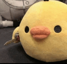 a stuffed duck with a knife in its mouth .