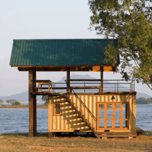 a small house with stairs leading up to a balcony overlooking a body of water .