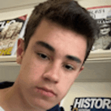 a close up of a young man 's face in front of a shelf with magazines on it .