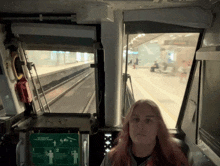 a woman sits in the driver 's seat of a train with a sign that says no smoking