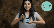 a woman is holding a jar with a spoon in her hand and a shop now circle in the background