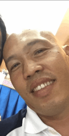 a close up of a man 's face with a blue curtain behind him