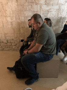 a man in a green shirt sits on a white cube