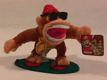 a stuffed donkey kong wearing sunglasses and a medal is standing on a green mat .