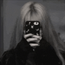 a black and white photo of a girl taking a selfie with her phone .