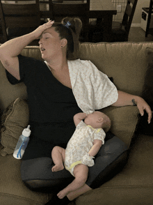 a woman is laying on a couch holding a baby