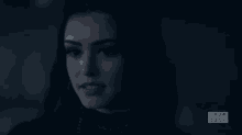 a close up of a woman 's face in a dark room with the words show case on the bottom right corner .