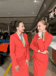 two women in red suits are standing next to each other in front of a counter with the number 28 on it