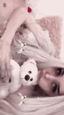 a woman is laying down with a teddy bear in her lap .