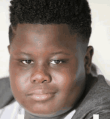 a close up of a young boy 's face with a gray sweater on