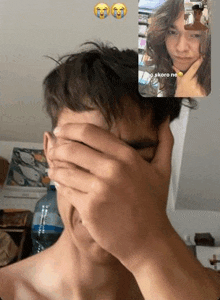 a man is covering his face while talking on a video call .