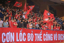 a large group of people are standing in a stadium holding flags and a banner .