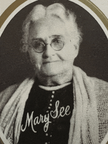 a black and white photo of a woman with mary see embroidered on her shirt