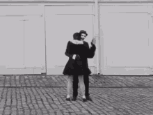 a man and a woman dancing on a cobblestone street