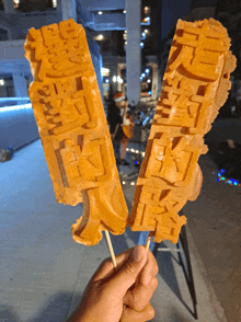 a person is holding two waffle sticks that say ' chinese ' on them