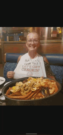 a woman is sitting at a table with a plate of food and holding a sign that says hot sauce