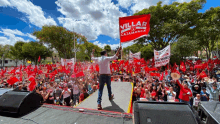 a man stands on stage holding a flag that says villar