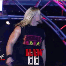 a wrestler is wearing a raw shirt and standing in a dark room