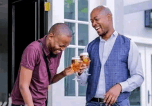 two men are standing next to each other holding glasses of wine and laughing .