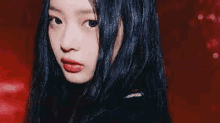 a close up of a woman 's face with long black hair and red lipstick .