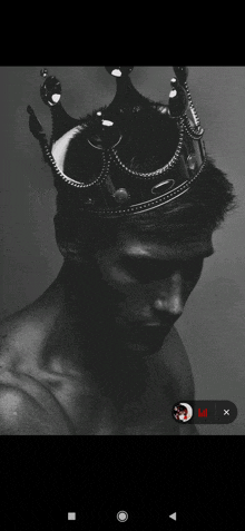 a man without a shirt is wearing a black crown on his head