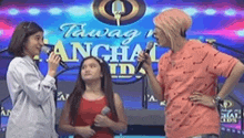 three girls singing into microphones in front of a sign that says tawag