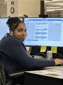 a woman sits in front of a computer with a sticky note on it that says ' invoice '