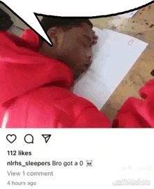 a man in a red hoodie is sleeping on a piece of paper on a table .