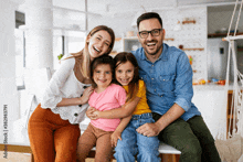 a family posing for a picture while sitting on a stool