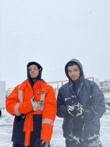 two men standing in the snow with one wearing a jacket that says castrol on it