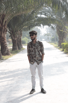 a man wearing sunglasses and a floral shirt is standing in the middle of a road