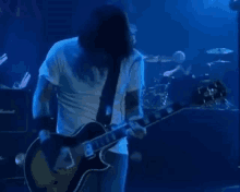 a man with long hair is playing a guitar on a stage in front of a marshall amplifier