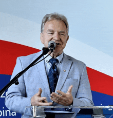 a man in a suit and tie is speaking into a microphone in front of a podium that says dina