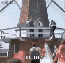 a group of people are standing in front of a windmill with the words `` like this '' written on the bottom .